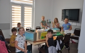 Siedmioro dzieci przy stole w trakcie zajęć plastycznych, patrzą w obiektyw