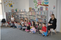 Dzieci siedza po turecku, sluchaja bibliotekarza.