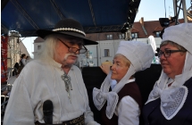 Mezczyzna w kapeluszu goralskim oraz dwie kobiety w ludowych, bialych czepcach