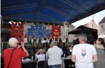 Dziewiec kobiet w strojach ludowych na scenie, przed nimi publicznosc