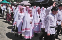 Grupa kobiet i mezczyzn w strojach ludowych w korowodzie